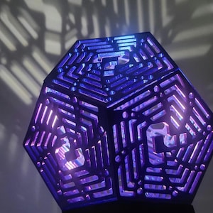 May include: A purple geometric lamp with a intricate design. The lamp is made of metal and has a light inside that shines through the design.