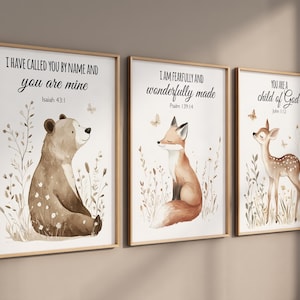 Puede incluir: Tres impresiones de acuarela con citas inspiradoras e ilustraciones de animales del bosque. La primera impresión presenta un oso marrón con la cita "Te he llamado por tu nombre y tú eres mío, Isaías 43:1". La segunda impresión presenta un zorro con la cita "Estoy hecho de manera asombrosa y maravillosa, Salmo 139:14". La tercera impresión presenta un ciervo con la cita "Eres un hijo de Dios, Juan 1:12".