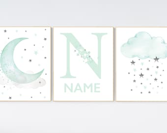 May include: Three framed prints with a watercolor theme. The first print features a crescent moon with stars, the second print features the letter N with stars, and the third print features a cloud with stars raining down.