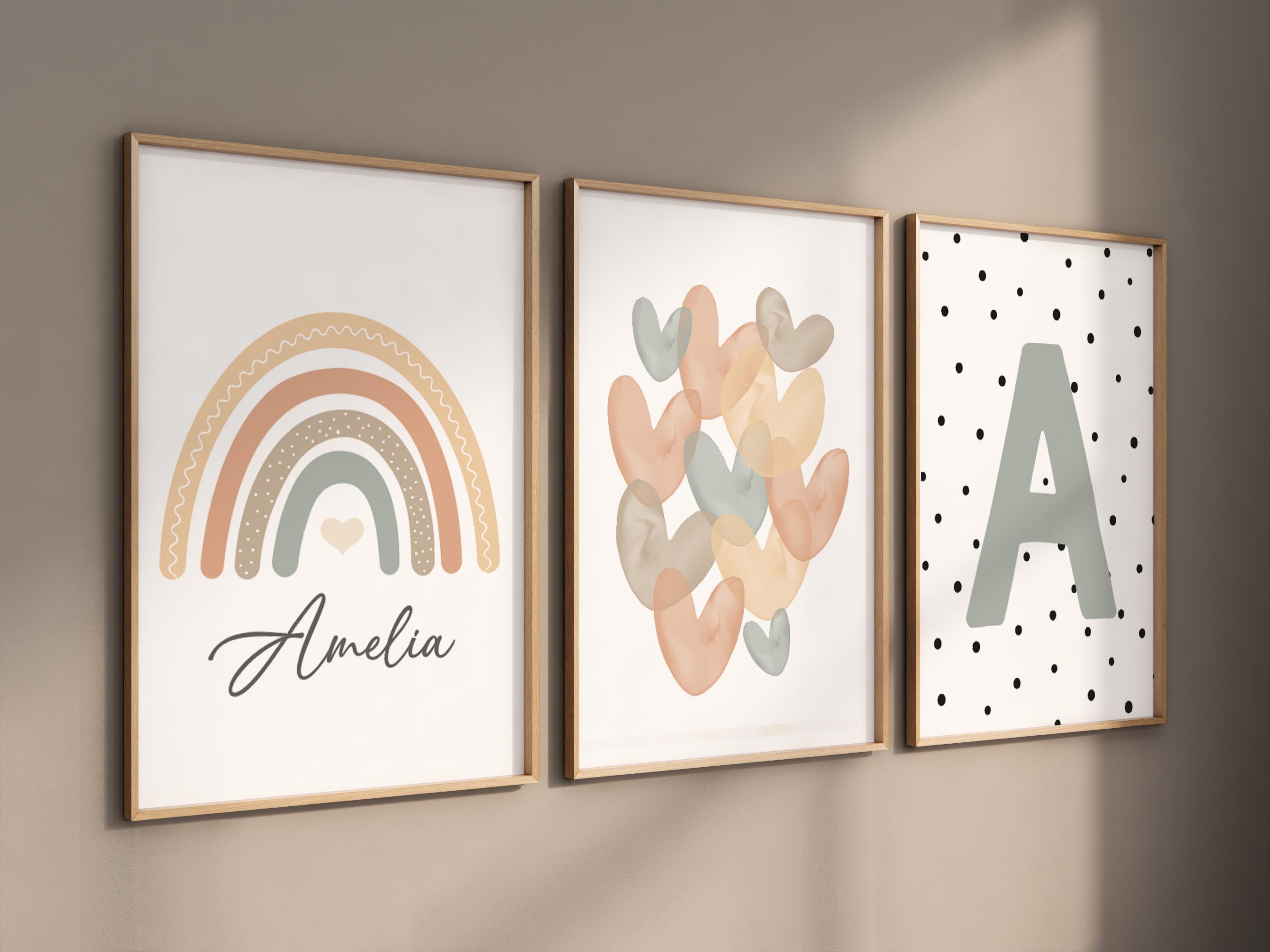 Pode incluir: Três impressões emolduradas com um tema boho. A primeira impressão apresenta um arco-íris com um coração no centro e o nome Amelia escrito abaixo. A segunda impressão apresenta um grupo de corações de aquarela em tons de pêssego, rosa e azul. A terceira impressão apresenta uma letra A grande em cinza sobre um fundo branco com bolinhas pretas.