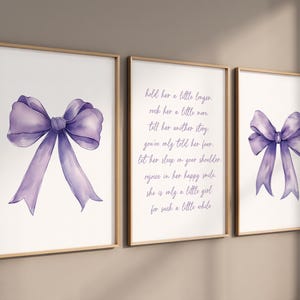 May include: Three printable wall art prints with a watercolor purple bow on each. The middle print has a poem about holding a little girl a little longer. The poem reads: "hold her a little longer, rock her a little more, till her another tiny, give only told her fear. Let her sleep in your shoulder, rejoice in her happy smile, she is only a little girl, for such a little while."