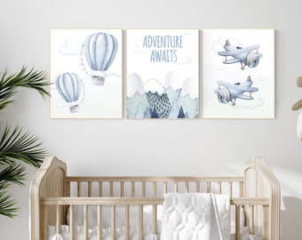 Puede incluir: Tres impresiones de acuarela azul y blanca para una guardería. La primera impresión presenta dos globos aerostáticos, la segunda impresión dice "La aventura te espera" con una escena de montaña, y la tercera impresión presenta dos aviones.
