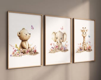 May include: Three framed prints featuring watercolor illustrations of a bear, elephant, and giraffe surrounded by flowers and butterflies. The prints have a white background and are framed in a light wood frame.