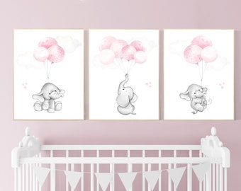 May include: Three watercolor prints of a gray elephant holding pink balloons. The elephant is flying in the air with clouds in the background. The prints are framed in a light wood frame.