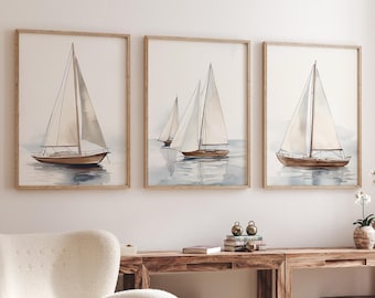 May include: Three framed watercolor paintings of sailboats on the water. Each painting features a wooden sailboat with white sails. The artwork has a neutral color palette with shades of brown, beige, and blue.