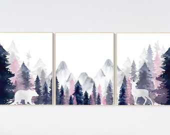 Op de afbeelding: Een set van drie aquarelprints met een bergketen, een bos en dieren. De prints zijn in tinten blauw, roze en grijs. De linker print toont een beer, de middelste print toont een bergketen en de rechter print toont een hert.