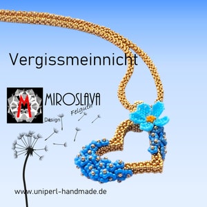 May include: Gold beaded necklace with a heart-shaped pendant adorned with blue beaded flowers and a central blue flower with an orange center. The text "Vergissmeinnicht" is displayed above the pendant, with the designer's logo and website address visible.