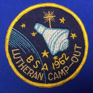 May include: A blue and gold embroidered patch with a white and blue rocket ship, stars, and the text "BSA 1962 LUTHERAN CAMP-OUT".