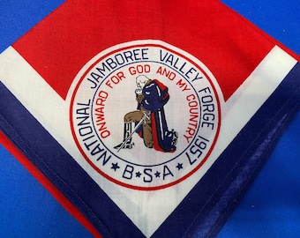Pode incluir: Um lenço de pescoço National Jamboree Valley Forge 1957 Boy Scouts of America (BSA) branco, vermelho e azul com um logotipo circular que apresenta uma figura ajoelhada e o texto "Onward For God And My Country".