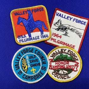 May include: Four embroidered patches with the words "Valley Forge" and various designs. One patch features a rider on a horse, another has a cannon, and two are circular with text and symbols. The patches are on a blue background.