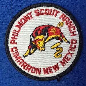 May include: A white embroidered patch with a red and black bull, a yellow snake, and the text "Philmont Scout Ranch Cimarron New Mexico".