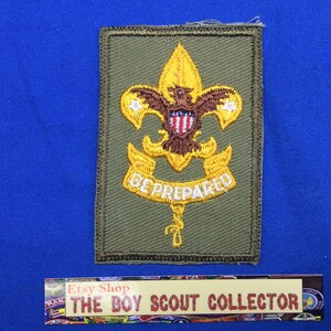 May include: A green Boy Scout patch with a yellow embroidered fleur-de-lis, eagle, and the words "Be Prepared".