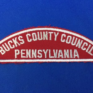 May include: Red and white embroidered patch with the text "Bucks County Council Pennsylvania".