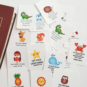 May include: A set of colourful flashcards with bible verses and cute animal illustrations. Each card features a different animal, such as a dinosaur, a squirrel, a hedgehog, a whale, a crab, a pineapple, a sun, and an owl. The cards are printed with inspirational bible verses, such as "Rejoice in the Lord always", "God has great plans for me", "Let your light shine", "It is by grace you have been saved", "Let everything that has breath praise the Lord", "Taste and see that the Lord is good", "In the beginning God created the heaven and the earth", "The heavens declare the glory of God", and "Give thanks to the Lord for He is good".