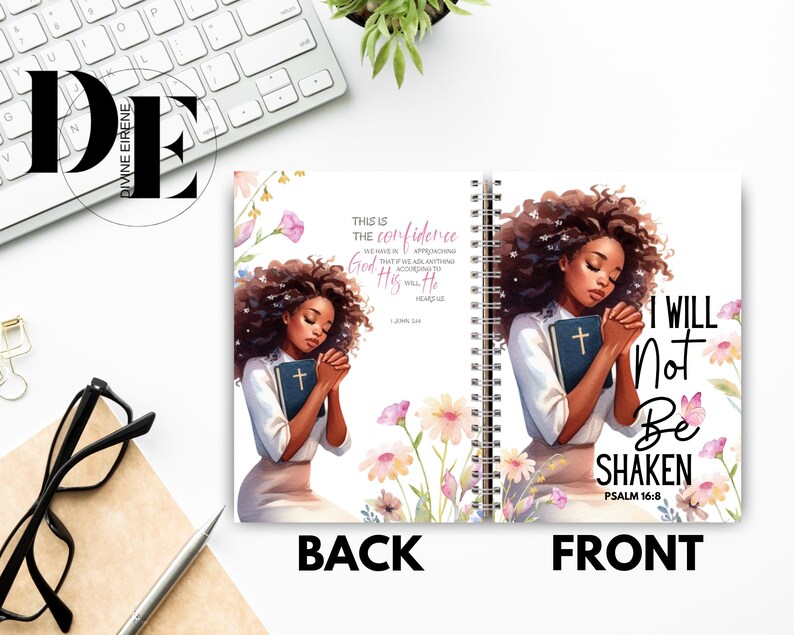 May include: A pink and white floral design with a black woman holding a bible. The text on the front of the journal reads "I will not be shaken Psalm 16:8". The text on the back of the journal reads "This is the confidence that we have in approaching God: that if we ask anything according to His will, He hears us."