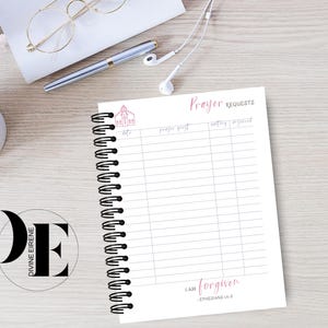 May include: A white prayer journal with a black spiral binding. The cover features a small pink church illustration and the text "Prayer Requests". The bottom of the journal has the text "I am forgiven - Ephesians 4:32".