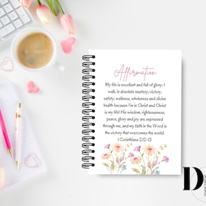 May include: A white spiral bound notebook with a pink floral design and the text "Affirmation" in pink. The text below reads "My life is excellent and full of glory; I walk in absolute mastery, victory, safety, wellness, wholeness and divine health because I'm in Christ and Christ is my life! His wisdom, righteousness, peace, glory and joy are expressed through me, and my faith in the Word is the victory that overcomes the world. I Corinthians 2-12-13".