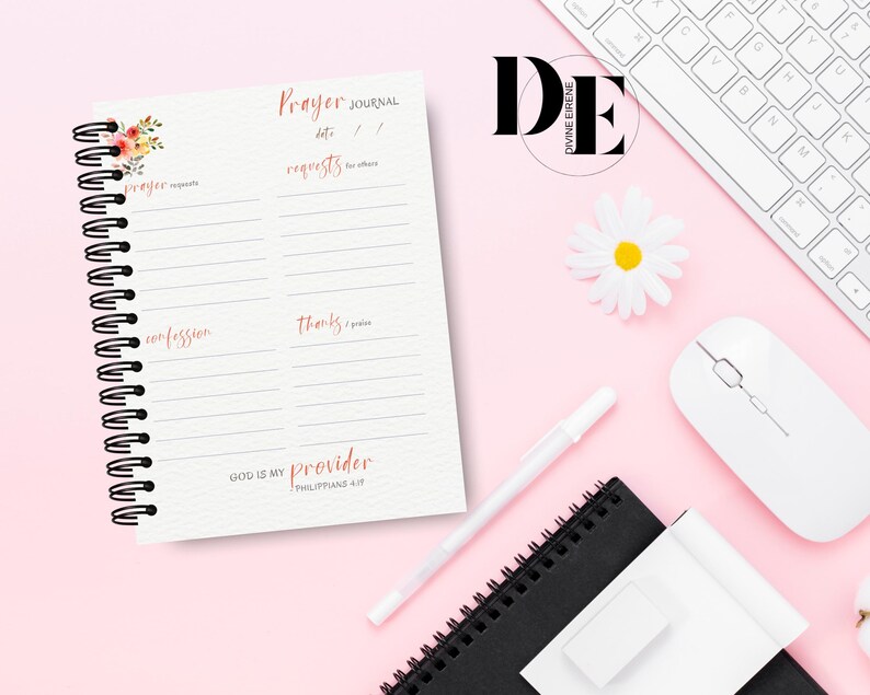 May include: A pink and white prayer journal with a floral design on the cover. The journal has a spiral binding and is divided into sections for prayer requests, confessions, and thanks. The text on the cover reads "Prayer Journal" and "God is my provider, Philippians 4:19".
