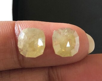 May include: Two light yellow, faceted, cushion-shaped gemstones.