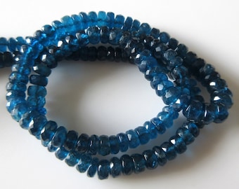 May include: A strand of dark blue faceted gemstone beads. The beads are round and have a slightly irregular shape.