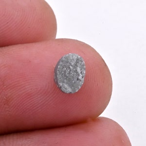 May include: A gray, oval-shaped gemstone with a rough, textured surface.