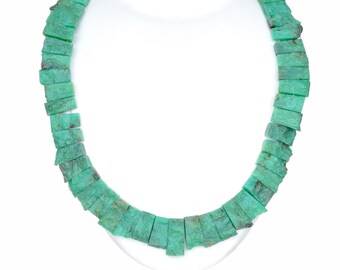 May include: A green gemstone necklace made of rectangular beads. The necklace is strung on a silver cord and is displayed on a white background.