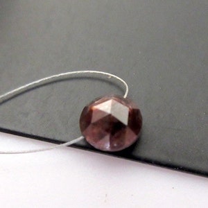 May include: A single, faceted, dark brown gemstone bead with a silver thread running through it.