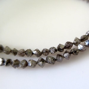 May include: A strand of dark grey, faceted diamond beads. The beads are small and have a rough, natural texture.