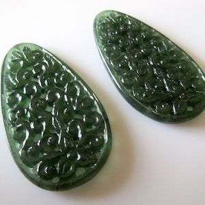 May include: Two green, carved, teardrop-shaped pendants with a floral design.