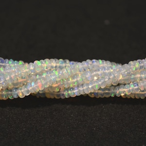 May include: A strand of white opal beads with iridescent flashes of color. The beads are round and smooth, and they are strung on a clear thread.