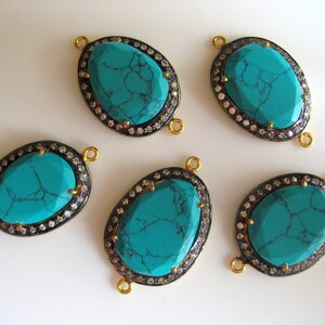 May include: Five turquoise gemstone connector charms with gold and black accents. Each charm features a turquoise stone surrounded by a halo of clear rhinestones.