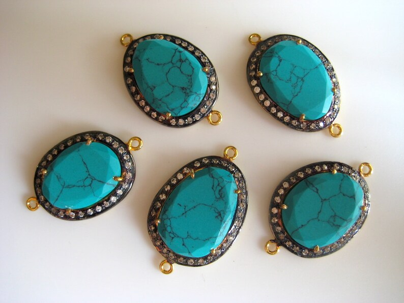 May include: Five turquoise gemstone connector charms with gold and black accents. Each charm features a turquoise stone surrounded by a halo of clear rhinestones.