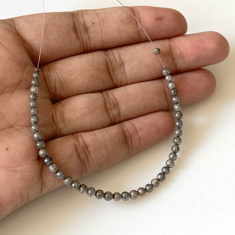 May include: A strand of silver-toned beads with a speckled finish. The beads are round and strung on a thin wire.