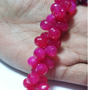 May include: A strand of pink faceted gemstone beads. The beads are round and have a smooth, polished finish.
