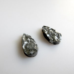May include: Two teardrop-shaped black stones with a rough, textured surface.