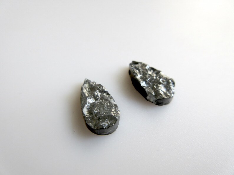 May include: Two teardrop-shaped black stones with a rough, textured surface.