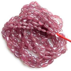 Op de afbeelding: Een streng roze ovale edelsteen kralen. De kralen zijn glad en gepolijst, met een lichte glans.