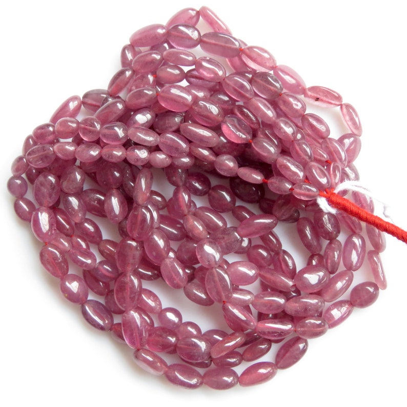 Op de afbeelding: Een streng roze ovale edelsteen kralen. De kralen zijn glad en gepolijst, met een lichte glans.