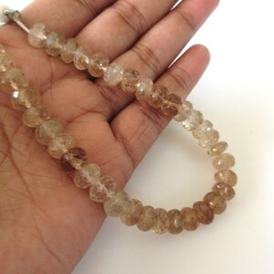 May include: A strand of faceted, translucent, light brown and clear quartz beads. The beads are round and have a slightly irregular shape. The strand is approximately 18 inches long.