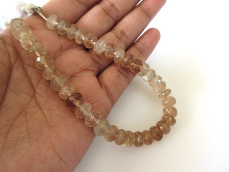 May include: A strand of faceted, translucent, light brown and clear quartz beads. The beads are round and have a slightly irregular shape. The strand is approximately 18 inches long.