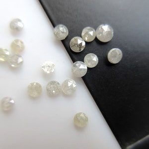 Könnte beinhalten: Eine Sammlung weißer Rohdiamanten, auch bekannt als Rohdiamanten, auf einer weißen und schwarzen Oberfläche. Die Diamanten sind in verschiedenen Größen und Formen.
