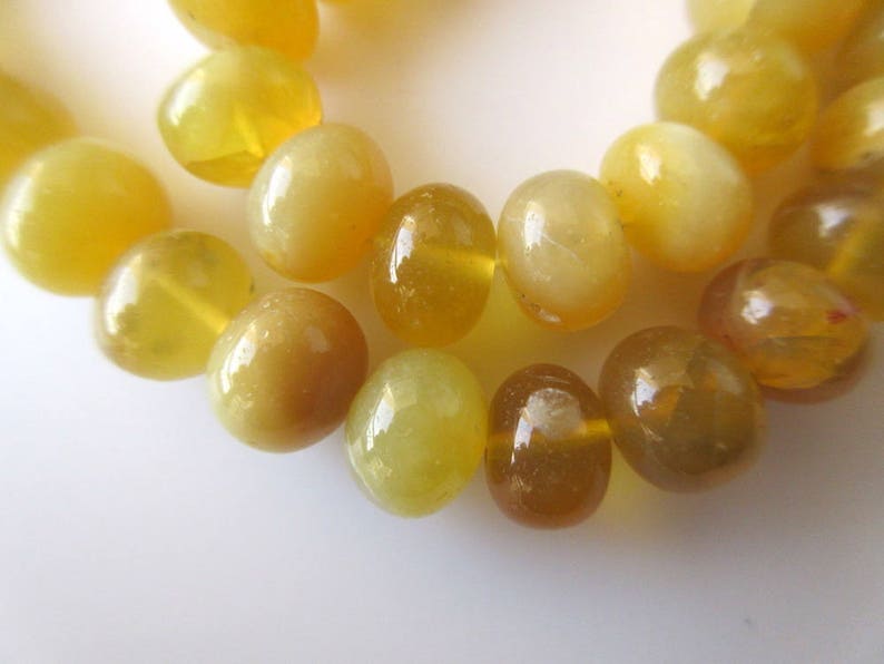 May include: A strand of yellow opal beads, each bead is smooth and round with a slight pearlescent sheen.