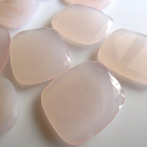 May include: A collection of eight pale pink, faceted, square-shaped chalcedony gemstones.