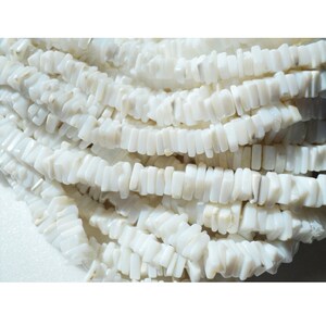 May include: A strand of white, rectangular, shell beads. The beads are smooth and have a slight iridescent sheen.