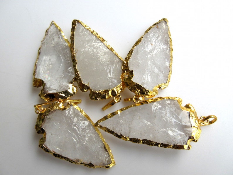 May include: Five clear quartz arrowhead pendants with gold-plated edges. The pendants have a raw, natural look and are perfect for jewelry making.