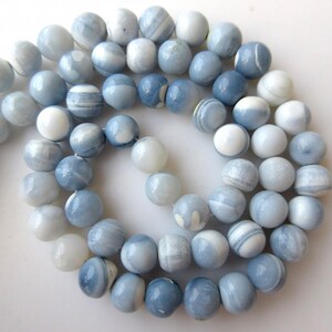 May include: A strand of blue and white agate beads. The beads are round and have a smooth, polished finish. They are perfect for making jewelry or other crafts.