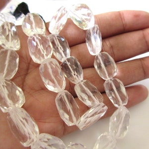 K&ouml;nnte beinhalten: Eine Str&auml;hne aus klaren Quarzkristallperlen, facettiert und oval geformt. Die Perlen sind auf einem durchsichtigen Faden aufgereiht und haben einen Durchmesser von etwa 10 mm.