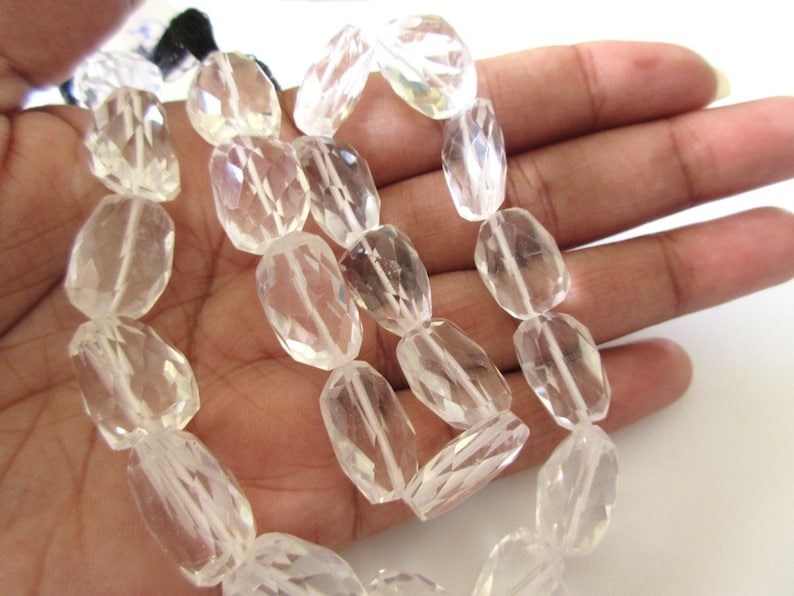 K&ouml;nnte beinhalten: Eine Str&auml;hne aus klaren Quarzkristallperlen, facettiert und oval geformt. Die Perlen sind auf einem durchsichtigen Faden aufgereiht und haben einen Durchmesser von etwa 10 mm.