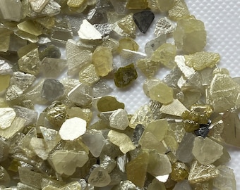 May include: A collection of small, rough, and irregularly shaped diamonds. The diamonds are a mix of clear, white, and yellow colours.