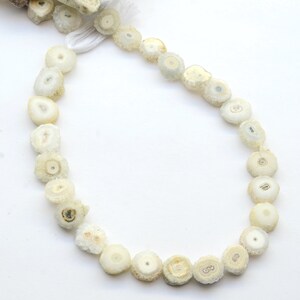 May include: A strand of white agate beads with a crystal-like appearance. The beads are round and have a natural, rough texture.
